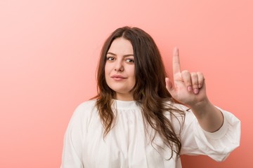 Young caucasian curvy woman standing against pink background