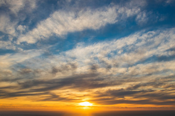 Obraz premium Dramatic golden rays over blue sunset or sunrise with clouds over the ocean.