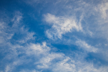 Fluffy white clouds on blue sky at sunset or sunrise.