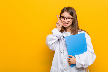 Little caucasian girl wearing a doctor costume smiling and raising thumb up