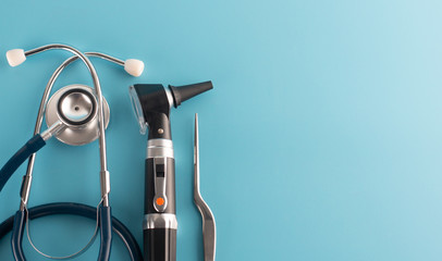 Otoscope with stethoscope on blue background.
