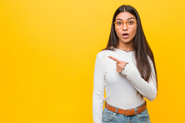 Young pretty arab woman against a yellow background pointing to the side