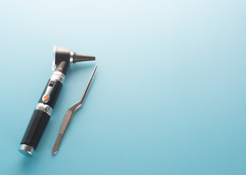 Otoscope with ear instrument on blue background.