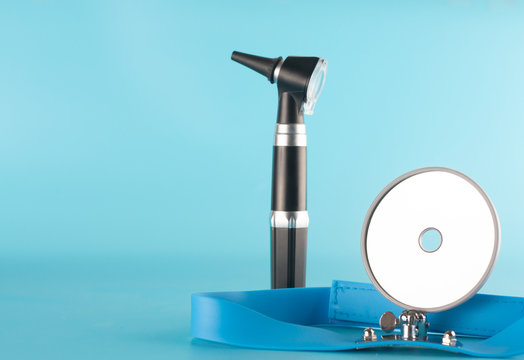 Otoscope with reflector mirror on blue background in health care concept.