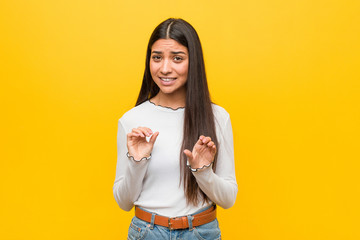 Young pretty arab woman against a yellow background rejecting someone showing a gesture of disgust.