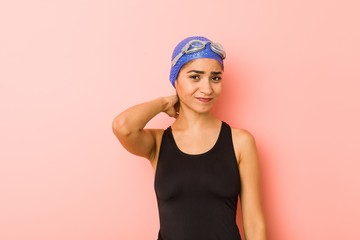 Young arab swimmer woman isolated touching back of head, thinking and making a choice.