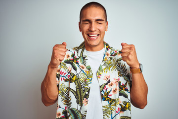 Young handsome man on holidays wearing Hawaiian shirt over white background excited for success with arms raised and eyes closed celebrating victory smiling. Winner concept.