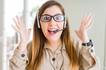 Beautiful young operator woman wearing headset at the office celebrating crazy and amazed for...