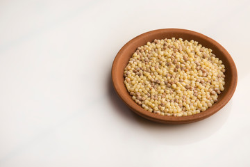 Fregola nel piatto di terracotta sfondo bianco