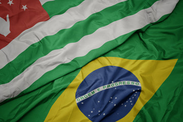 waving colorful flag of brazil and national flag of abkhazia.