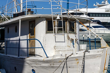Fishing boat moored at the dock. A typical old fishing boat anchored in the harbor along with modern yachts in the background
