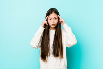 Young pretty chinese woman focused on a task, keeping forefingers pointing head.