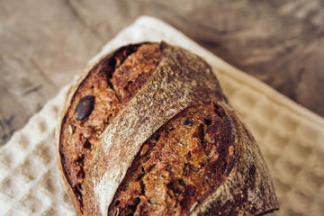 Brown fresh bread with seeds are cut into pieces on old wood background. Top view, copy space