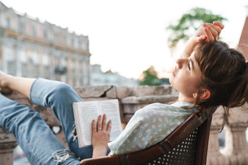 Young beautiful woman with book on a balcony.