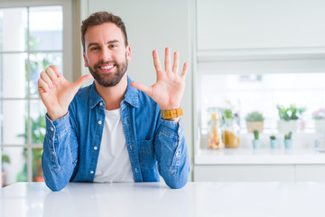 Handsome man at home showing and pointing up with fingers number six while smiling confident and happy.
