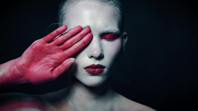 Mystery weird girl close half of her face with bloody hand