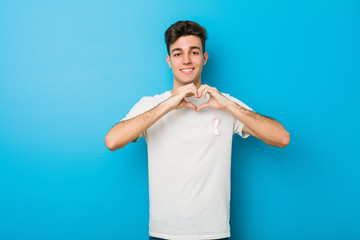 Teenager caucasian man with a pink bow. Concept of fight against cancer.