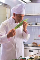 Confident mature chef smelling onion leaves at kitchen restaurant