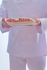 Midsection of chef holding fresh cherry tomatoes in tray at restaurant