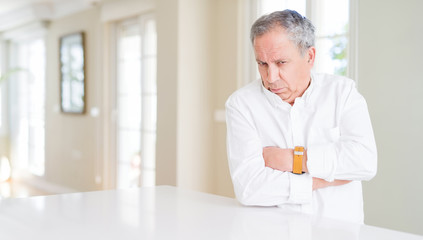 Handsome senior man at home skeptic and nervous, disapproving expression on face with crossed arms. Negative person.