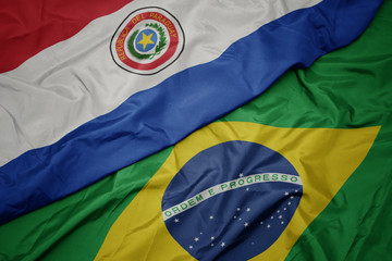 waving colorful flag of brazil and national flag of paraguay.