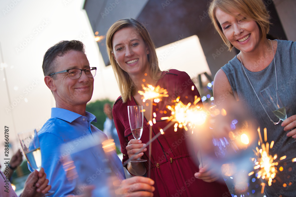 Canvas Prints Smiling business colleagues holding sparklers during party on rooftop