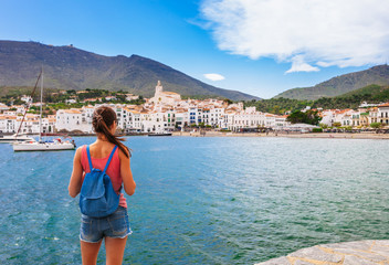 Tourist woman in Cadaques, Catalonia, Spain near of Barcelona. Scenic old town with nice beach and clear blue water in bay. Famous resort destination in Costa Brava with Salvador Dali landmark