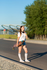 stylish girl in white stockings walking with longboard