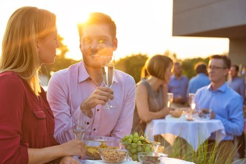 Smiling business colleagues standing at table during rooftop party