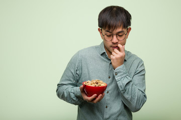 Young chinese man eating a cereals bowl