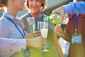 Businessman pouring wine from bottle to colleagues during success party