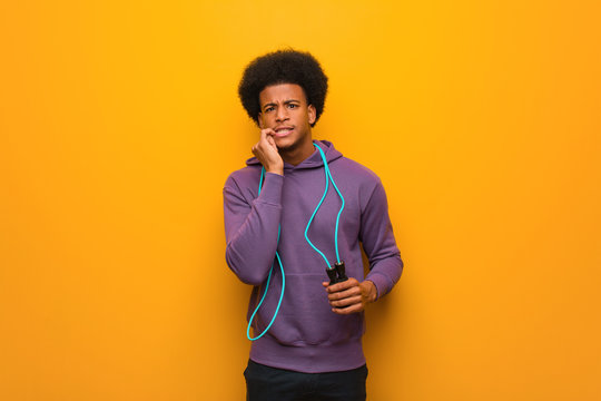 Young african american sport man holding a jump rope biting nails, nervous and very anxious