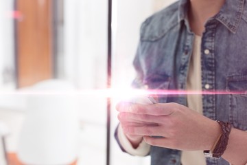 Fototapeta premium Male professional texting on smartphone in office with pink lens flare in background