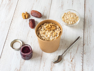 Oatmeal porridge with dates in a cardboard cup. Healthy food and diet concept.