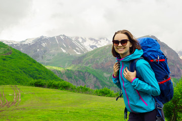 Cheerful women with backpack traveling in mountain. Joyful female traveler with sunglasses smile and looking at camera