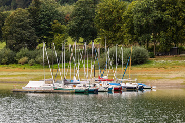Obraz premium Small quay and port of pleasure sailboats on the german Hennesee lake in the Sauerland region on an overcast day