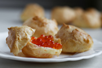 Homemade profiteroles with red caviar with on light background. Sea food