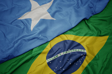 waving colorful flag of brazil and national flag of somalia.