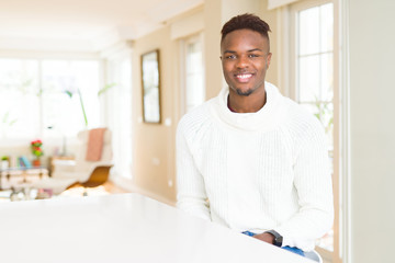 Handsome african american man on white table with a happy and cool smile on face. Lucky person.