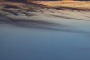 Cumulus sunset clouds with sun setting down on dark background
