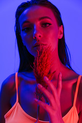 Image of gorgeous brunette woman wearing bodysuit underwear posing at camera with plant