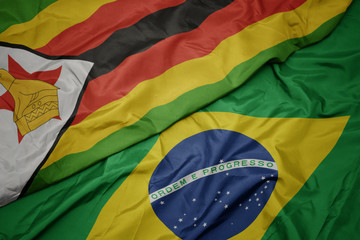 waving colorful flag of brazil and national flag of zimbabwe.