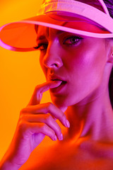 Image closeup of sexual brunette woman wearing sun visor cap and sportswear posing at camera