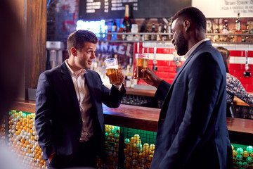 Two Businessmen Making A Toast As They Meet For Drinks And Socialize In Bar After Work