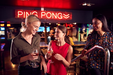 Three Female Friends Climbing Stairs As They Meet For Drinks And Socialize In Bar