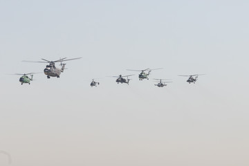 Many helicopters flying in the gray overcast sky