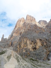 The peaks of the Dolomites of the Sassolungo Massif immersed in the clouds and in the nature of Trentino - Alto - Adige, Near the town of Canazei, Italy - August 2019.