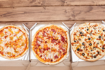 Italian pizza in cardboard box on wooden table. Top view
