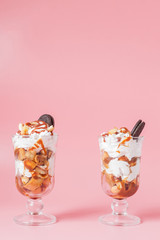 Sweet dessert in glass with biscuit and whipped cream on pink bsckground, selective focus and blank space