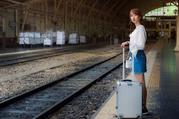 Asian woman is standing on platform and waiting train in the train station